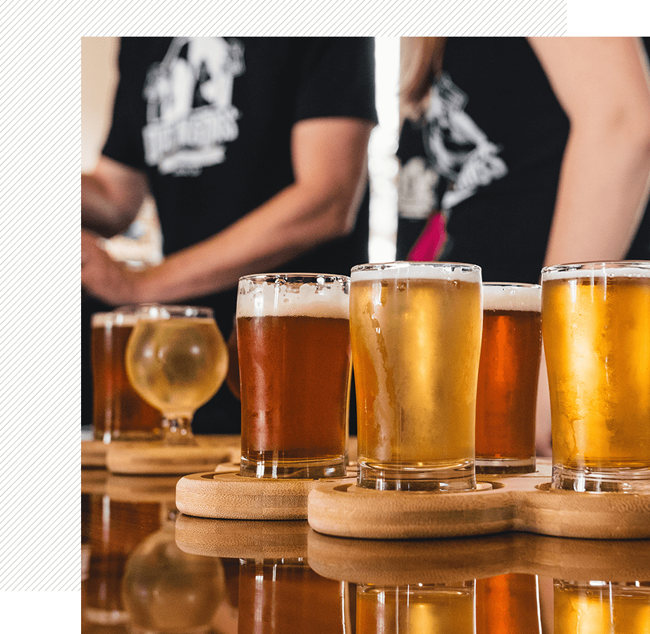 Assorted beers on wooden coasters at bar.