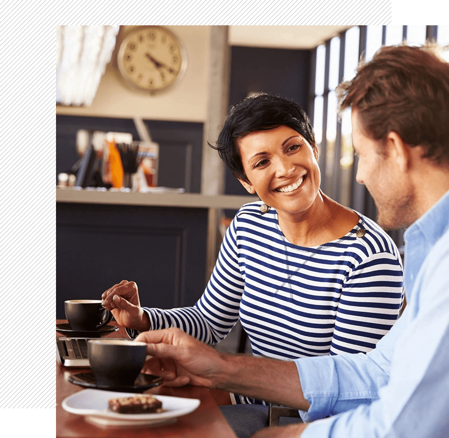 Two people smiling at a cafe table.